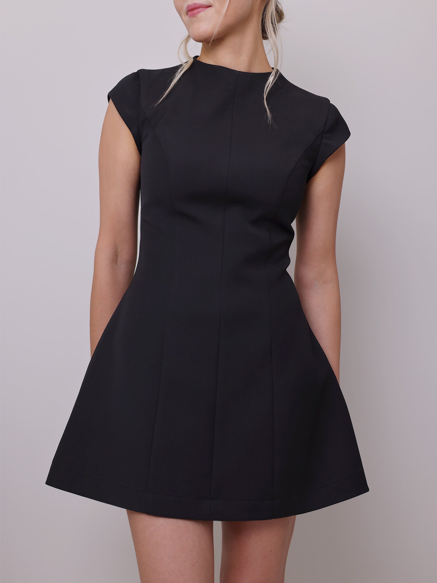 Front view of a black mini dress sewing pattern featuring A-line silhouette, cap sleeves, high neckline, and cinched waist.
