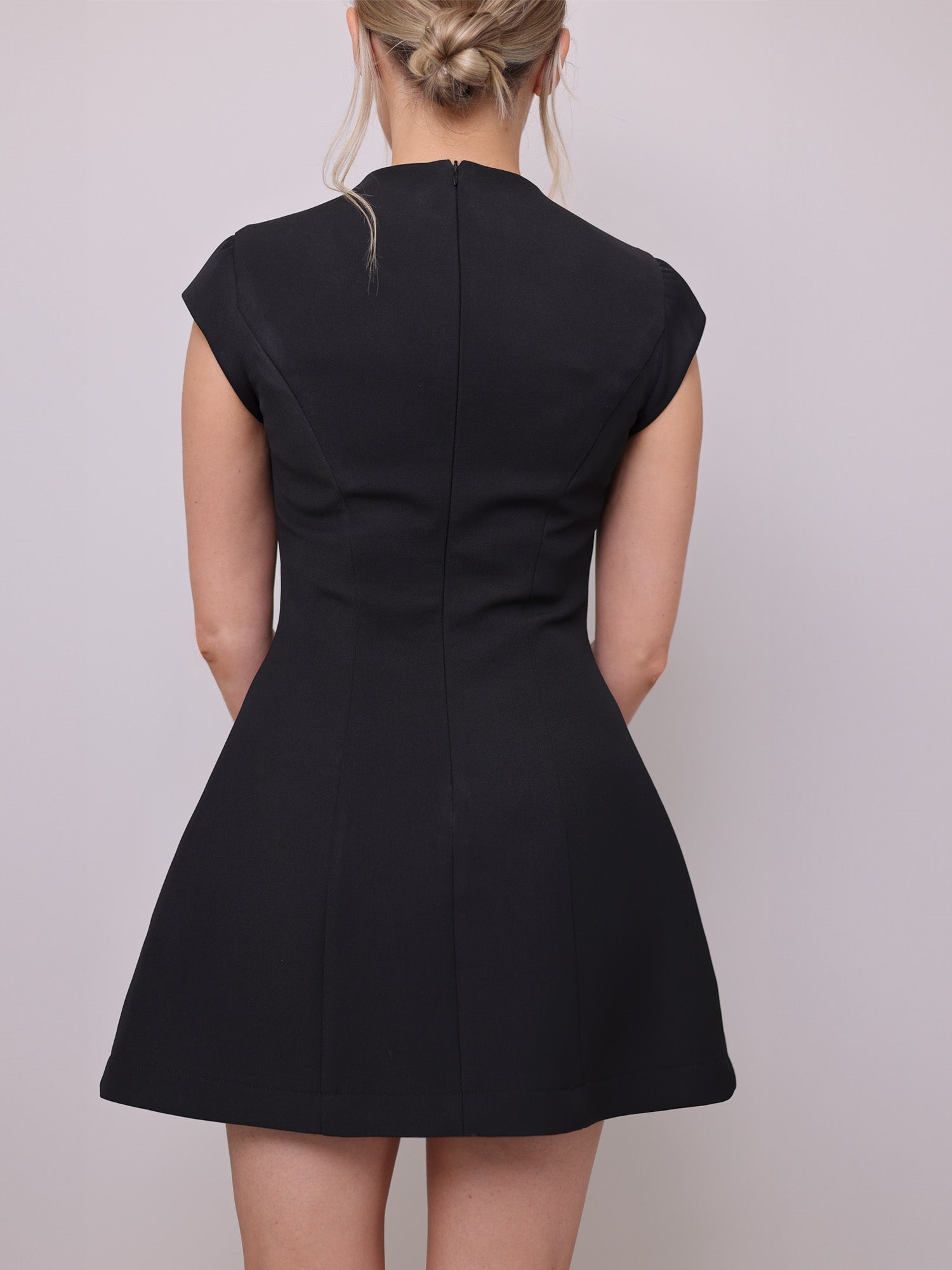 Back of the black mini dress sewing pattern featuring cap sleeves, a cinched waist, and a tailored A-line silhouette.