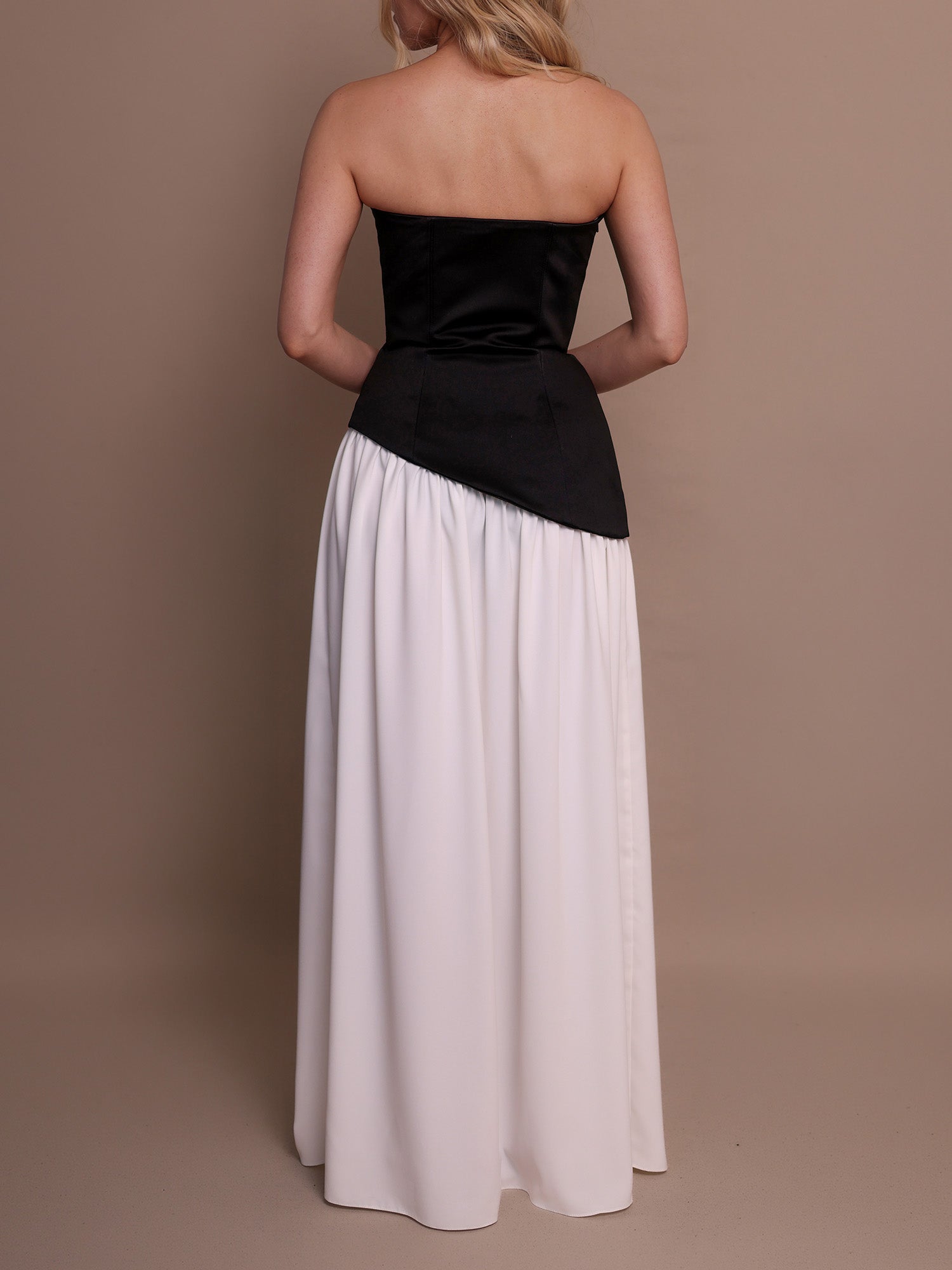 Woman wearing a black and white strapless dress sewing pattern with asymmetric hem.