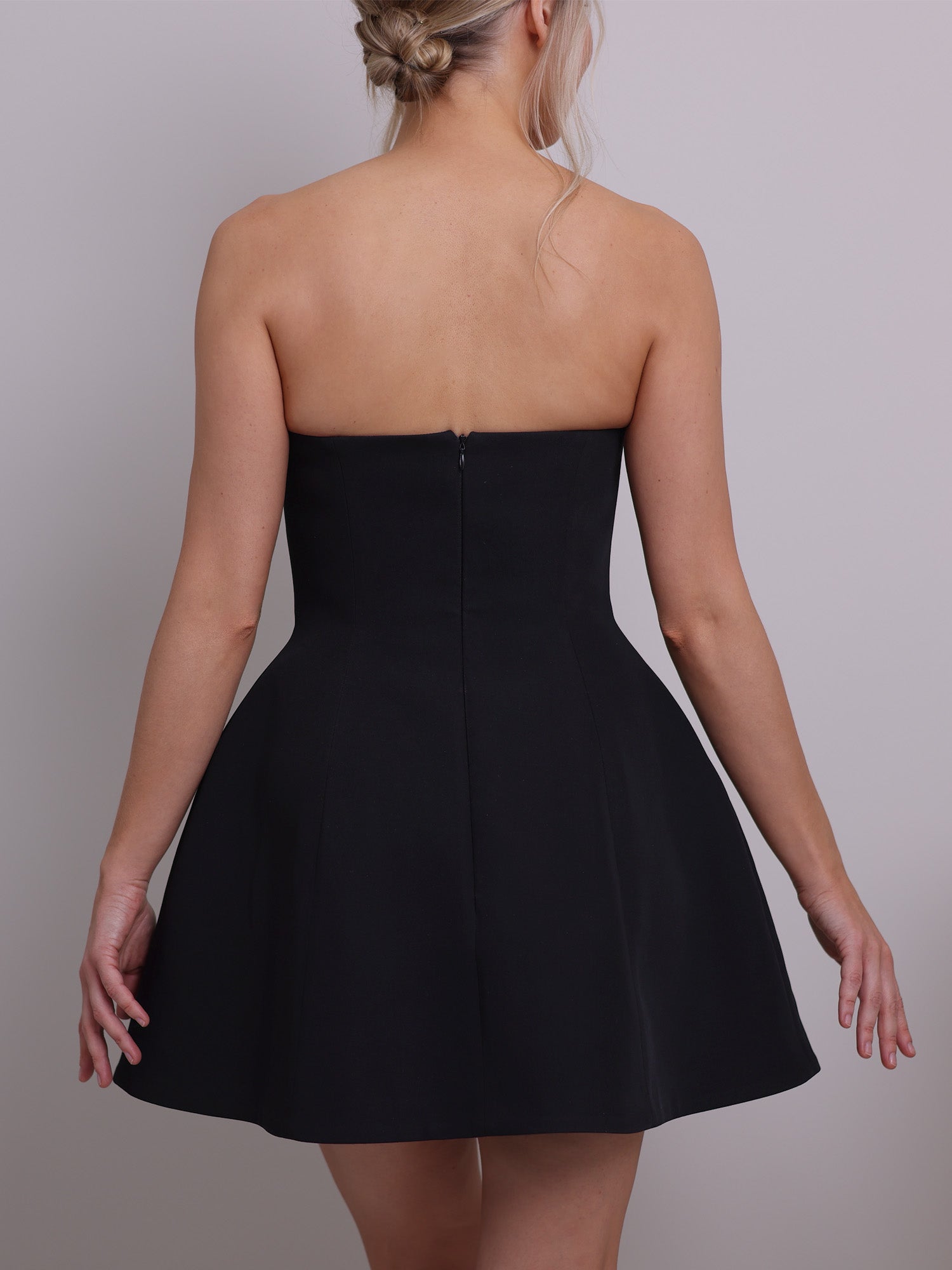 Back view of the strapless mini corset dress sewing pattern, featuring a boned bodice and dramatic bell-shaped skirt in black fabric.